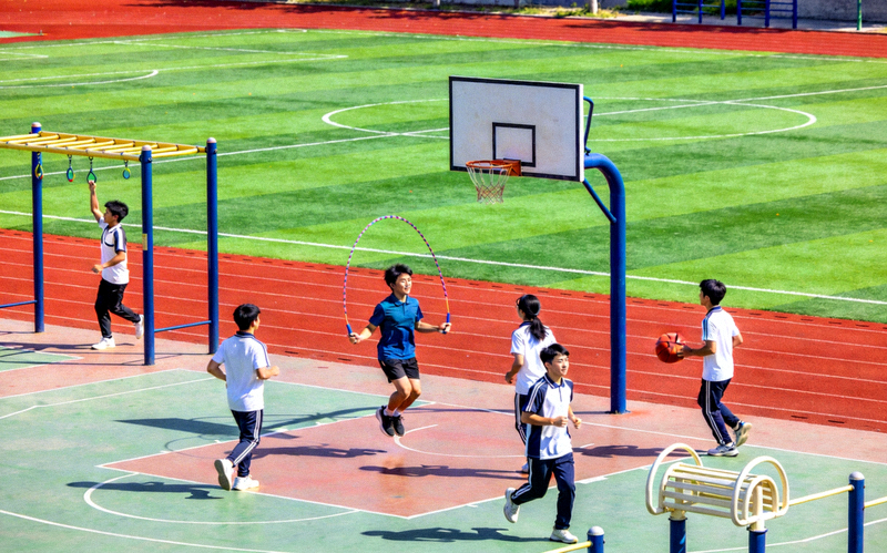 现代化学校操场，学生正在进行体育活动